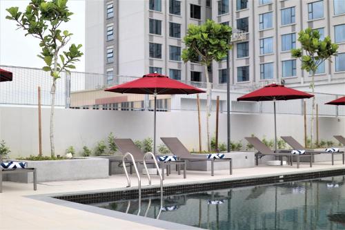 a pool with chairs and umbrellas next to a building at KSL ESPLANADE HOTEL with HOT SPRING in Klang