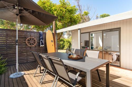 a table and chairs on a deck with an umbrella at Point Lonsdale Beach House - Relax Beach Surf Golf in Point Lonsdale
