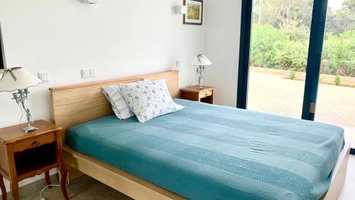 a bedroom with a bed with blue sheets and a window at Casa Penina in Portimão