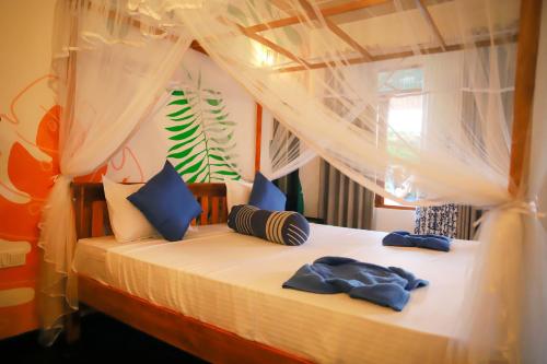 a bedroom with a bed with white sheets and blue pillows at Ruwan Jungle Homestay in Mirissa