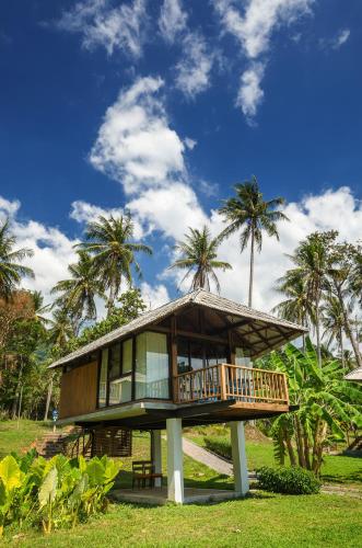 a house with a wrap around porch and palm trees at Tinidee Hideaway Tonsai Beach Krabi - SHA Extra Plus in Tonsai Beach