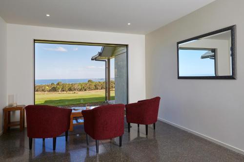 a dining room with a table and chairs and a large window at Koura Bay Golf Resort in Kaikoura