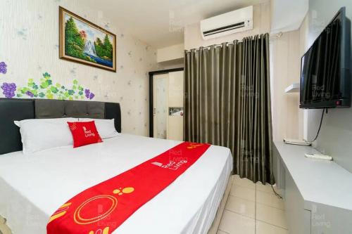 a bedroom with a bed with a red blanket at RedLiving Apartemen Serpong Green View - Hapukh Room Tower B in Ciater-hilir