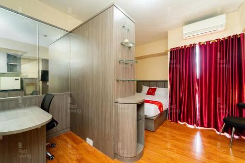 a bedroom with a bed and a red curtain at RedLiving Apartemen Serpong Green View - Hapukh Room Tower B in Ciater-hilir