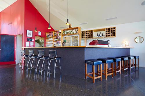 a bar in a restaurant with stools at Koura Bay Golf Resort in Kaikoura