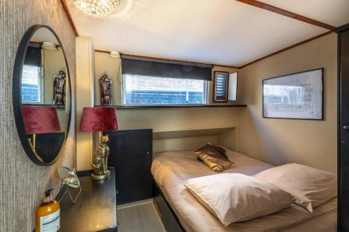 a small bedroom with a bed and a mirror at The luxury Boat in Zwolle