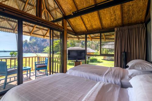 a bedroom with two beds and a balcony with a television at Tinidee Hideaway Tonsai Beach Krabi - SHA Extra Plus in Tonsai Beach