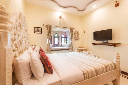 a bedroom with a white bed and a tv at Sunset Escape by VEO - Part of StayVista in Jodhpur
