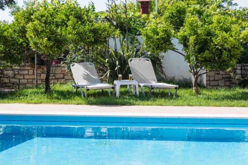 dos sillas blancas sentadas junto a una piscina en Afroditi 4 Villa, en Margarítai