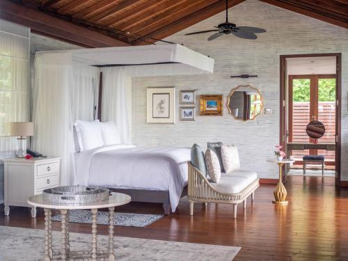 a bedroom with a bed and a chair and a table at Four Seasons Resort Seychelles in Baie Lazare Mahé