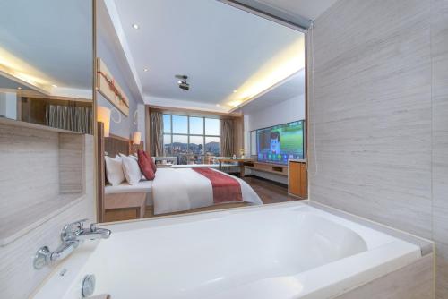 a bathroom with a tub and a bed and a mirror at Shenzhen Ramada Plaza, North Railway Station in Shenzhen