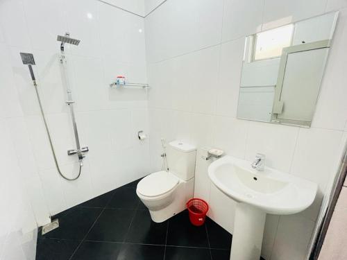 a white bathroom with a toilet and a sink at Yala Visit Villa in Tissamaharama