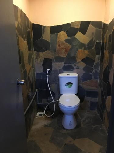 a bathroom with a toilet with a stone wall at The Train Hotel Hatyai in Hat Yai
