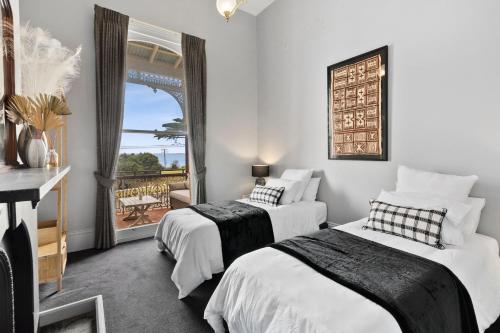 two beds in a room with a balcony at Pelicans at the Ozone in Queenscliff