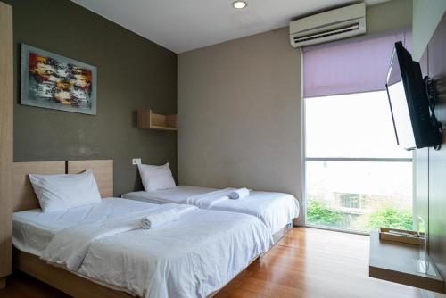 2 aparte bedden in een kamer met een televisie bij 3J Living in Binong