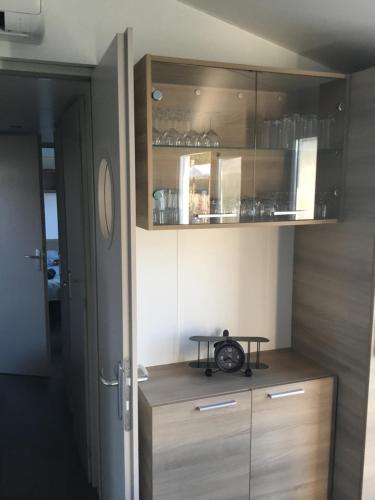 a kitchen with a wooden cabinet with a clock on it at Mobilhome2frejus in Fréjus