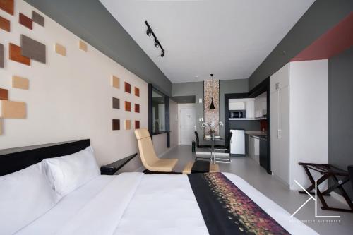 a bedroom with a large white bed and a kitchen at KL Serviced Residences Managed by HII in Manila