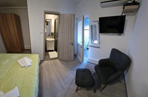 ペロイにあるApartments Vucericのベッド、椅子、テレビが備わるホテルルームです。