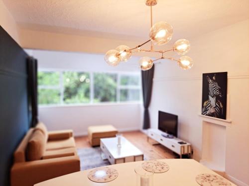 a living room with a couch and a chandelier at Secure Modern 2 bed - excellently located in Cape Town