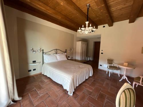 1 dormitorio con cama, mesa y lámpara de araña en Agriturismo Il Torriglione, en La Morra