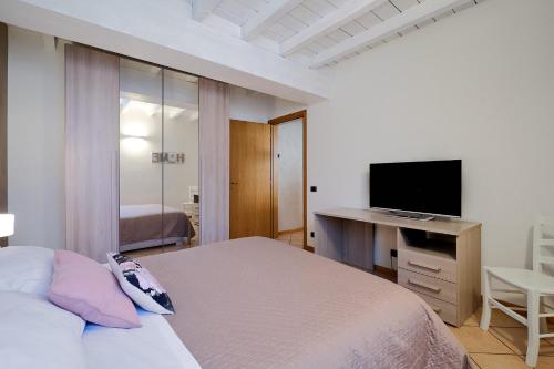 a bedroom with a bed and a desk with a television at Domus Dea Città Alta in Bergamo