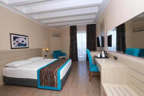a hotel room with a bed and a desk and chairs at Kaila Beach Hotel - All Inclusive in Alanya