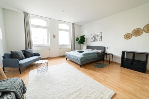 a bedroom with a bed and a couch and a tv at Full House Apartment MCity L10 in Magdeburg
