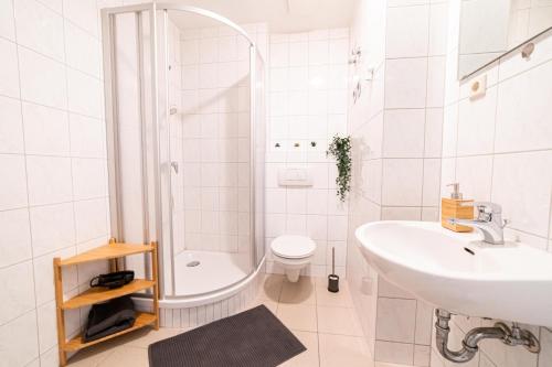 a white bathroom with a shower and a sink at Full House Apartment MCity L10 in Magdeburg