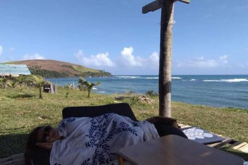 a woman laying on a couch next to the ocean at Daldagons View Deck 