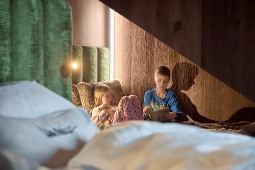 two children sitting on a bed reading a book at Luxury Chalet Vilaiet in Ortisei
