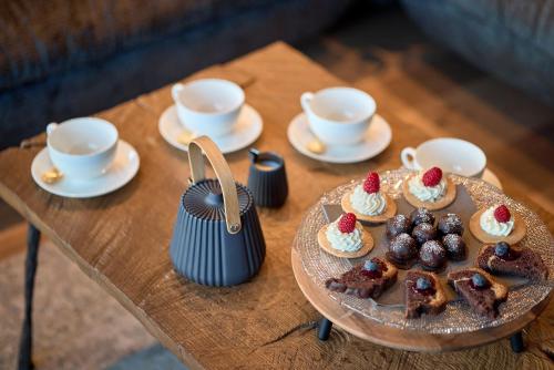 a table with a plate of cupcakes and cups of coffee at Luxury Chalet Vilaiet in Ortisei