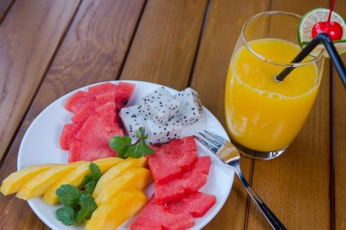 a plate of fruit and a glass of orange juice at Hanoi Amber Hotel in Hanoi