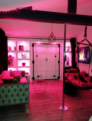 un salon avec un canapé et une chambre avec un éclairage rose dans l'établissement Gîte romantique avec SPA cœur à corps 44, à La Plaine-sur-Mer