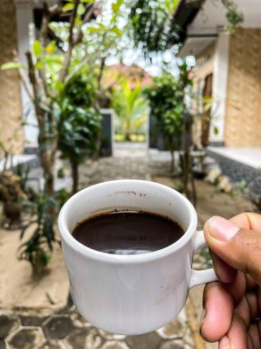 a person holding a cup of coffee on a table at Pandan Wangi in Nusa Lembongan