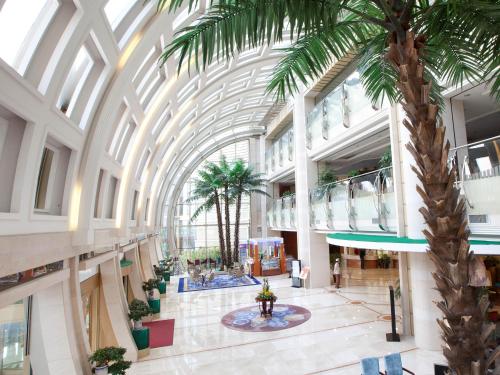 a large building with a palm tree in therium at Bayshore Hotel Dalian in Dalian