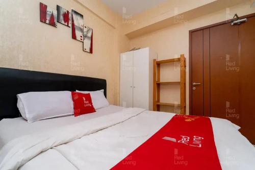 een slaapkamer met een bed met rode en witte kussens bij RedLiving Apartemen Green Lake View Ciputat - Pelangi Rooms 2 Tower E in Tangerang