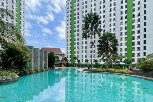 a large swimming pool in front of two tall buildings at RedLiving Apartemen Green Lake View Ciputat - Pelangi Rooms 2 Tower E in Tangerang