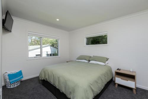 a white bedroom with a bed and a window at Cobham Crib - Anakiwa Holiday Home in Anakiwa