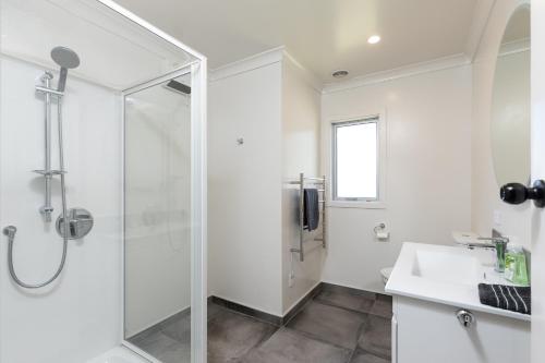 a white bathroom with a shower and a sink at Cobham Crib - Anakiwa Holiday Home in Anakiwa