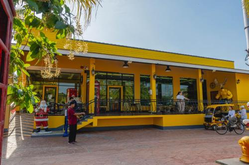 a yellow building with people standing outside of it at Apinya Resort Bangsarey in Ban Tao Than