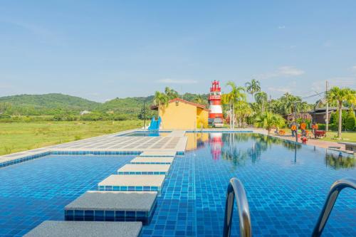a swimming pool with a lighthouse in the background at Apinya Resort Bangsarey in Ban Tao Than