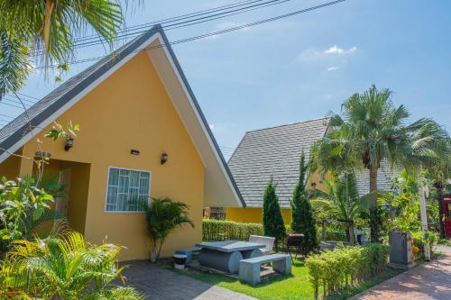a yellow house with a bench and a table at Apinya Resort Bangsarey in Ban Tao Than