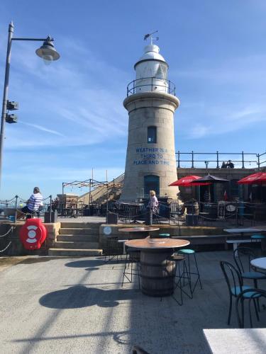a lighthouse with tables and chairs in front of it at Unique seafront 2 bedroom 2 bathroom apartment in Folkestone