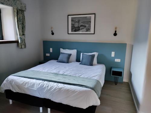 a bedroom with a large bed with a blue headboard at Hotel Le Moulin Des Ramiers in Crupet