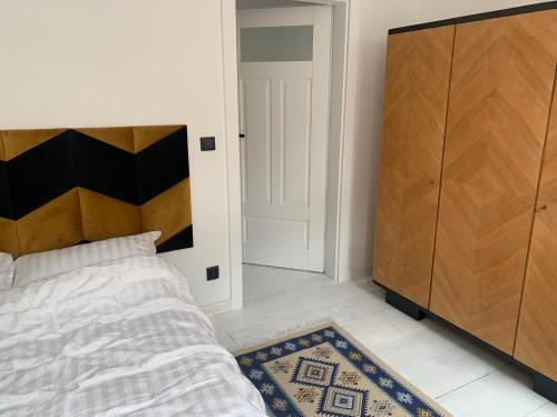 a bedroom with a bed and a wooden cabinet at Apartament Warszawska 33 in Mrągowo