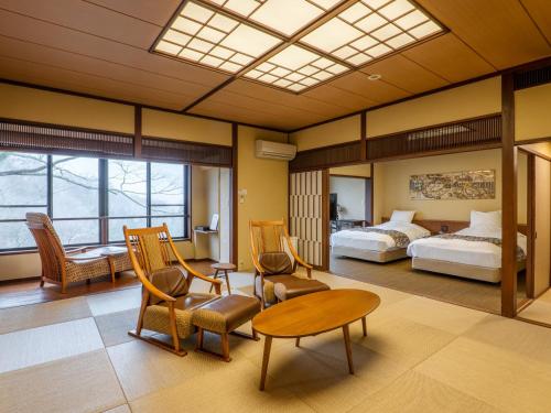 Habitación de hotel con cama, mesa y sillas en Kishigon Ryokan, en Shibukawa