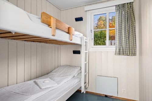 a bunk bed in a small room with a window at First Camp Norsjø Telemark in Akkerhaugen