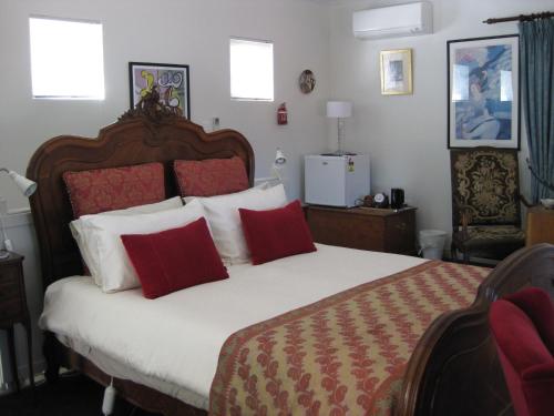 a bedroom with a large bed with red and white pillows at Three Chimneys Bed and Breakfast Boutique Guest House in Albany