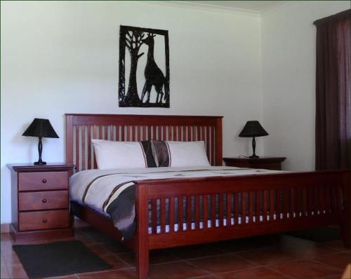 a bedroom with a large bed with two night stands and two lamps at Riverbend Self Catering Cottages in Magaliesburg