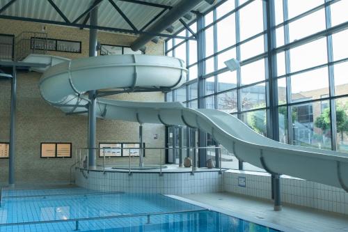 an indoor swimming pool with a slide in a building at Vildbjerg Sports Hotel & Kulturcenter in Vildbjerg